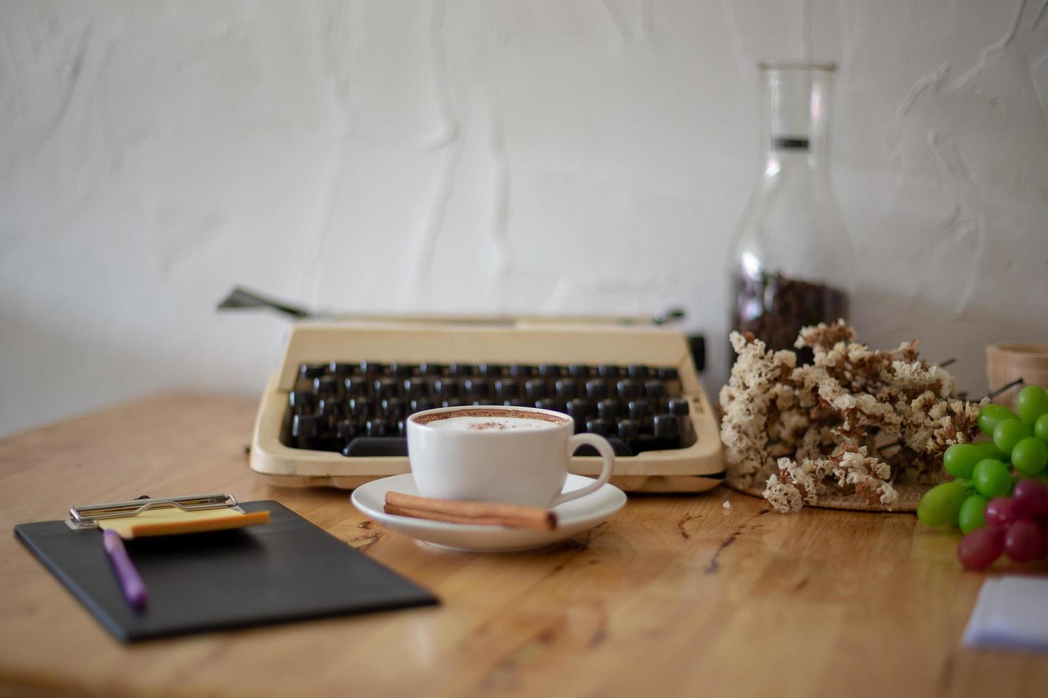 Vintage-Schreibmaschinen und Tasse Kaffee auf Holztisch foto