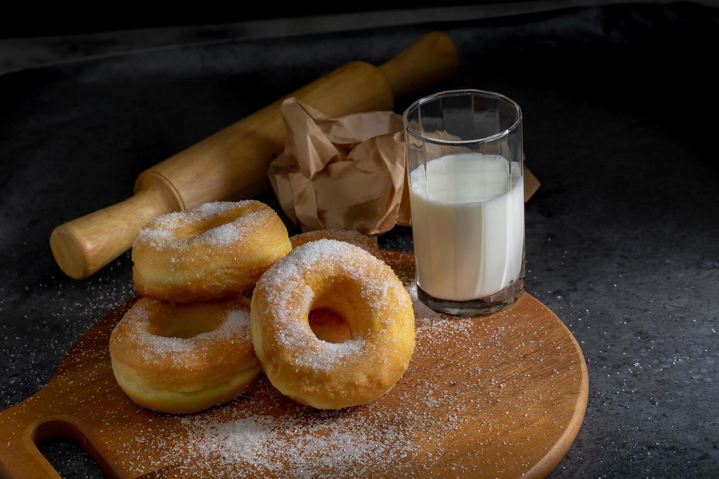 Donuts mit Zucker auf einer Holzplatte über einem dunklen Tischhintergrund. foto