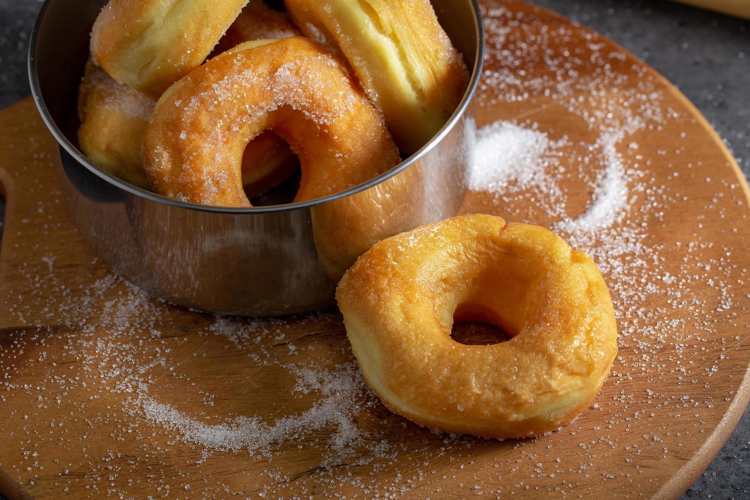 Donuts mit Zucker auf einer Holzplatte über einem dunklen Tischhintergrund. foto