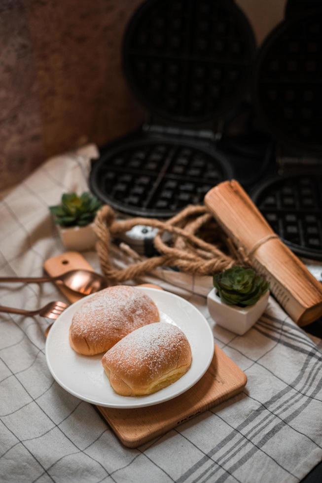 weiches Butterbrötchen mit Puderzucker auf einem Holzteller foto