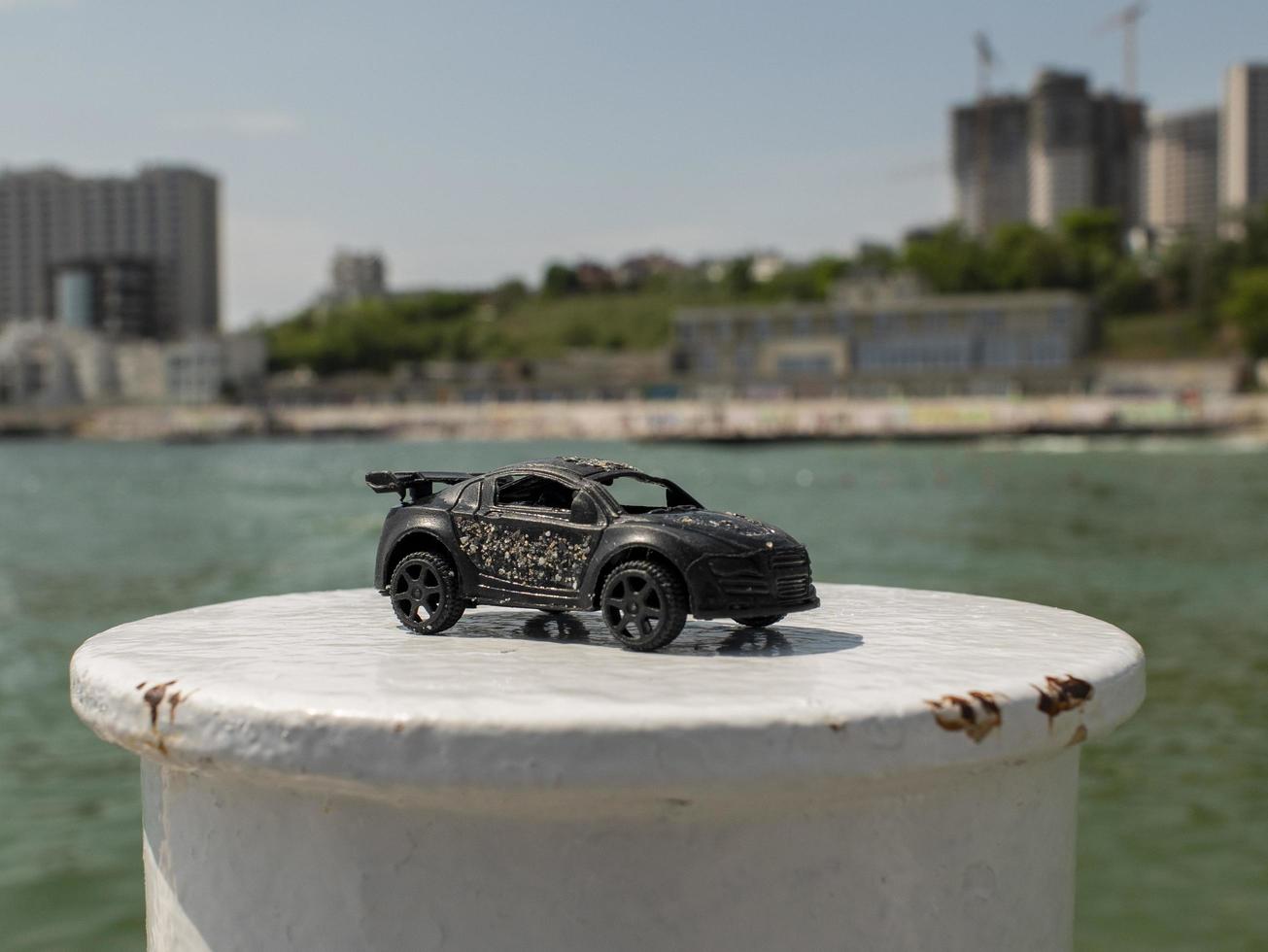 Spielzeugautomodell in Schwarz vor dem Hintergrund des Meeres und der Hochhäuser foto