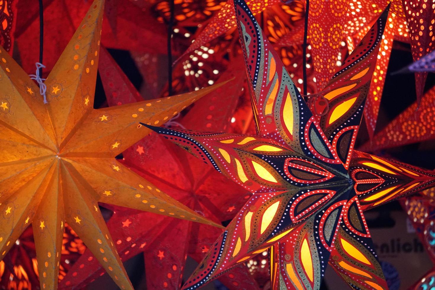 Lichter in der Dunkelheit. rote und goldene traditionelle sterne als weihnachtslaternen auf dem markt. foto