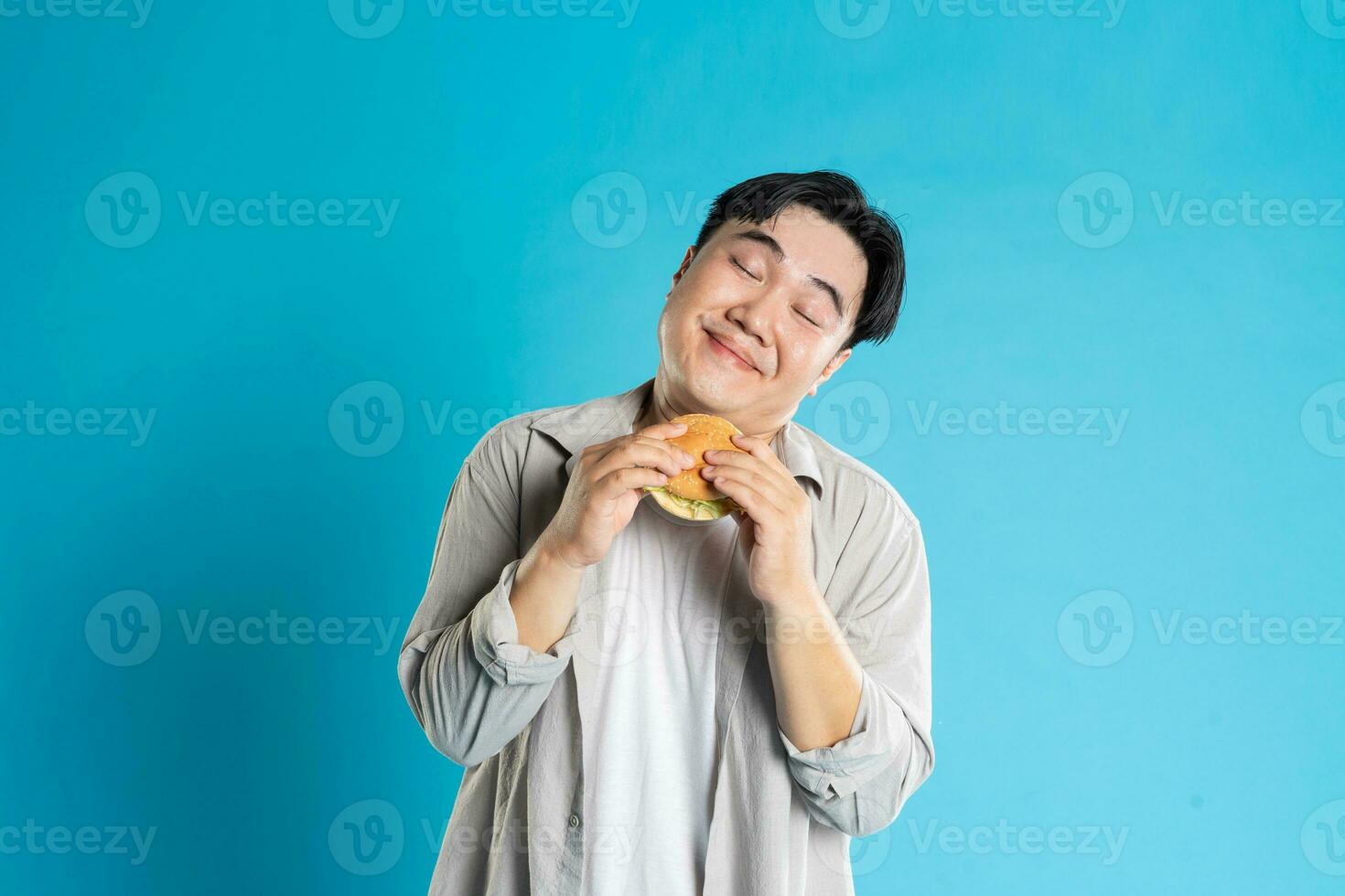 Porträt von asiatisch Mann Essen schnell Essen auf Blau Hintergrund foto