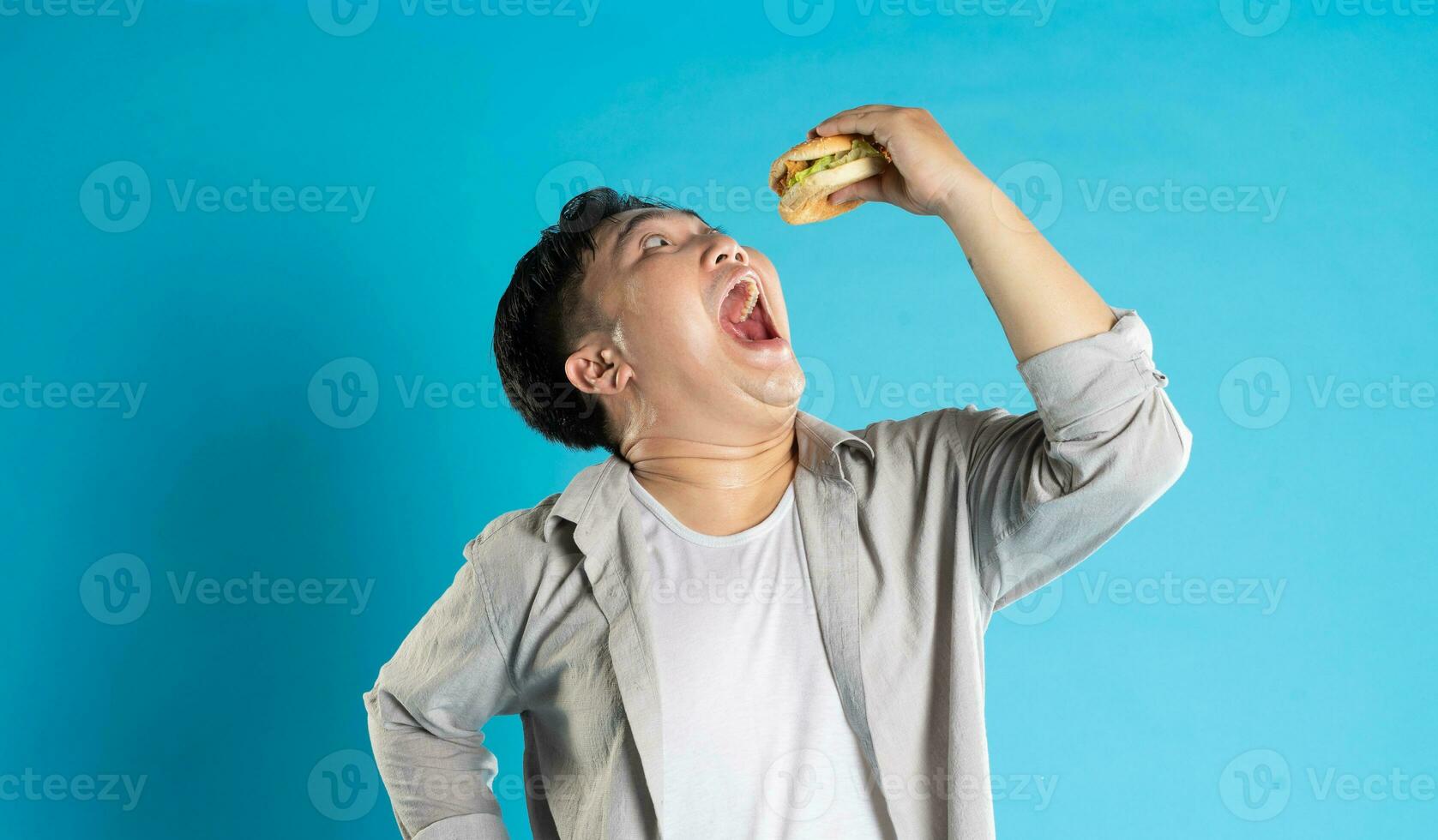 Porträt von asiatisch Mann Essen schnell Essen auf Blau Hintergrund foto