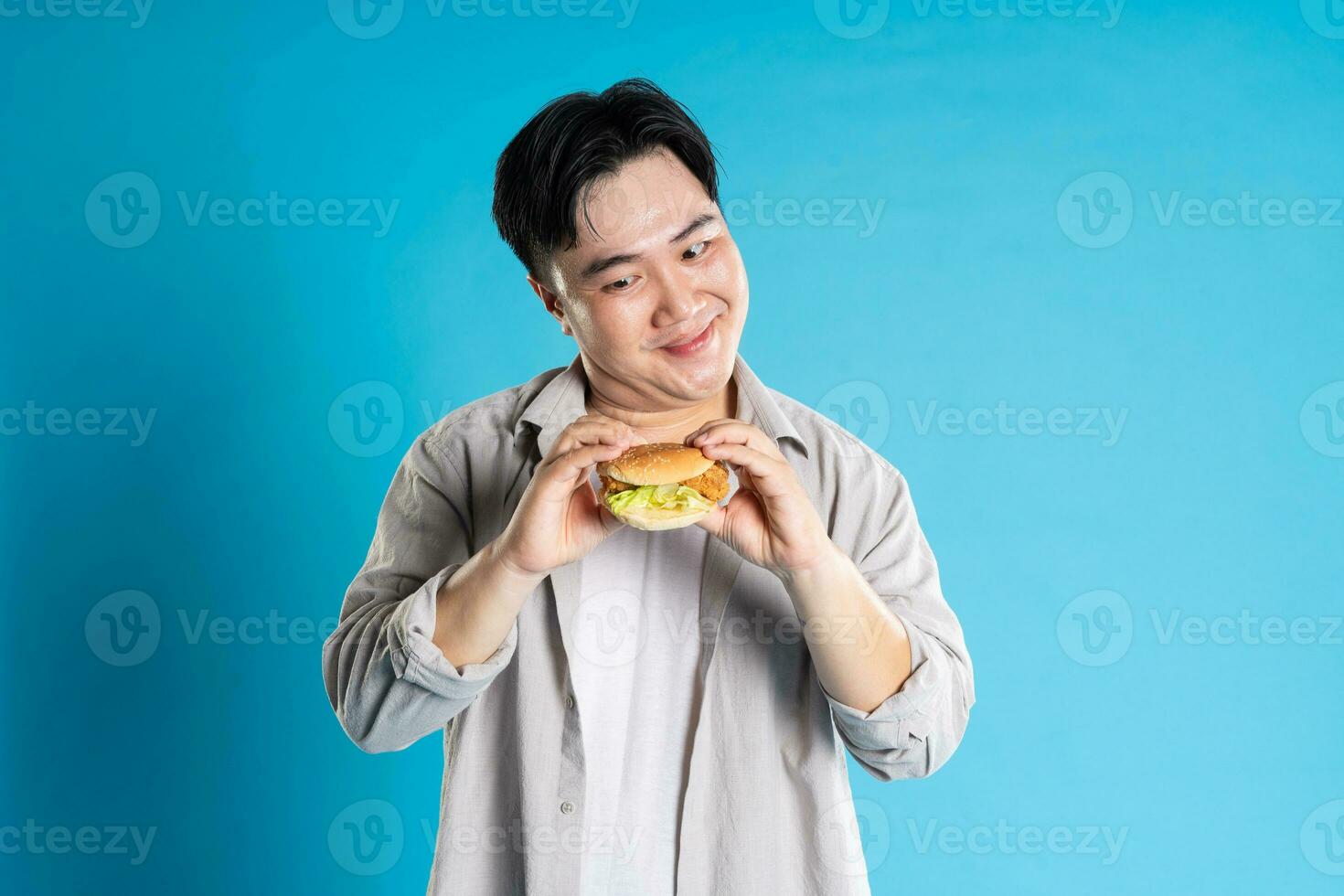 Porträt von asiatisch Mann Essen schnell Essen auf Blau Hintergrund foto