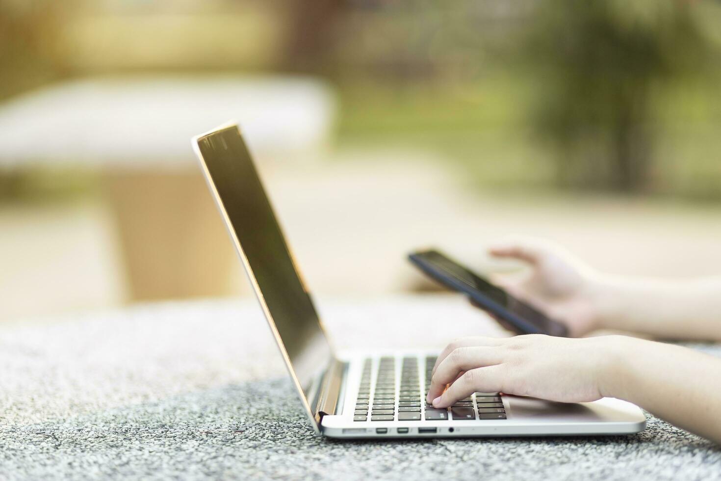 Nahansicht von Geschäft weiblich Arbeiten mit Laptop und Smartphone im beim das Park auf Büro draussen. foto