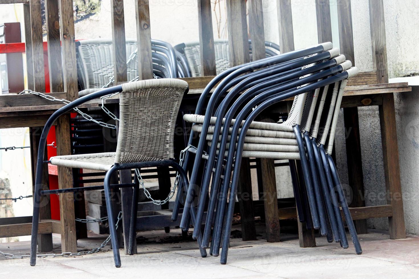 gestapelte Stühle in der Nähe von Cafétischen, die auf der Straße stehen foto