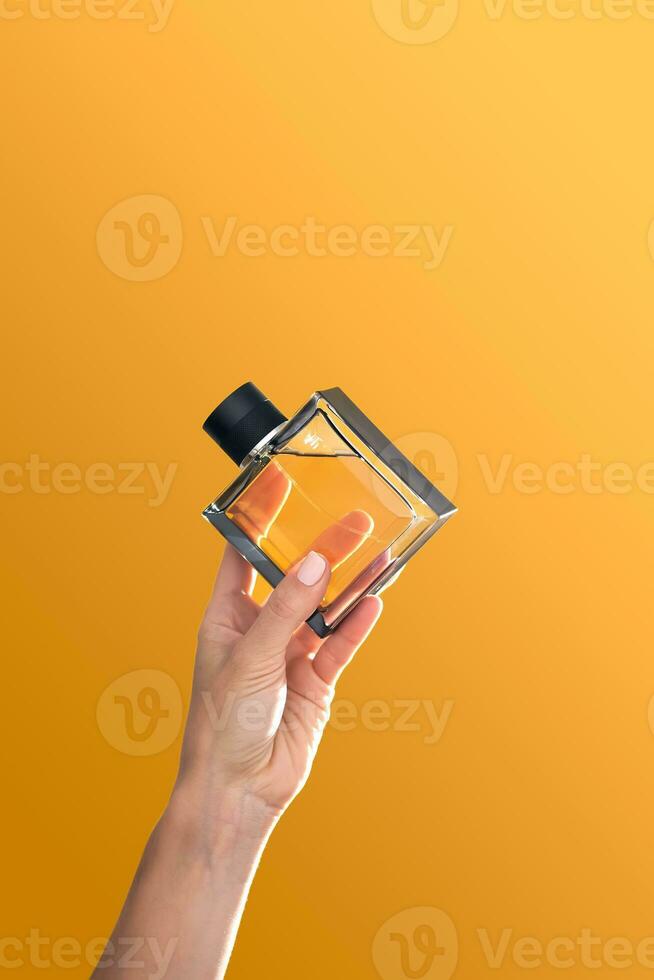 Parfüm Flasche im Hände auf ein Orange Hintergrund. foto