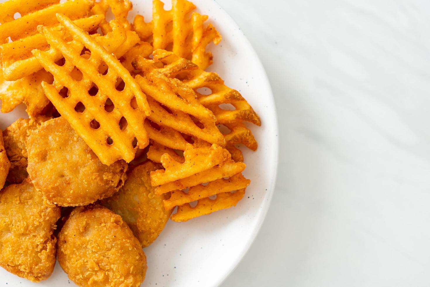 gebratene Chicken Nuggets mit Bratkartoffeln auf Teller foto