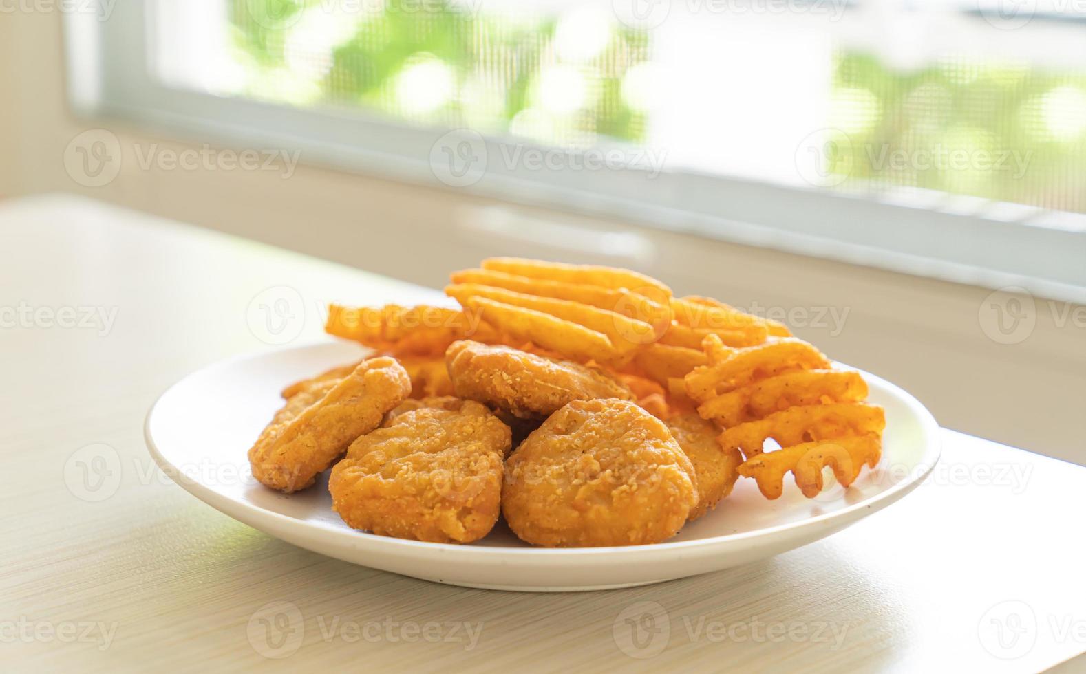 gebratene Chicken Nuggets mit Bratkartoffeln auf Teller foto