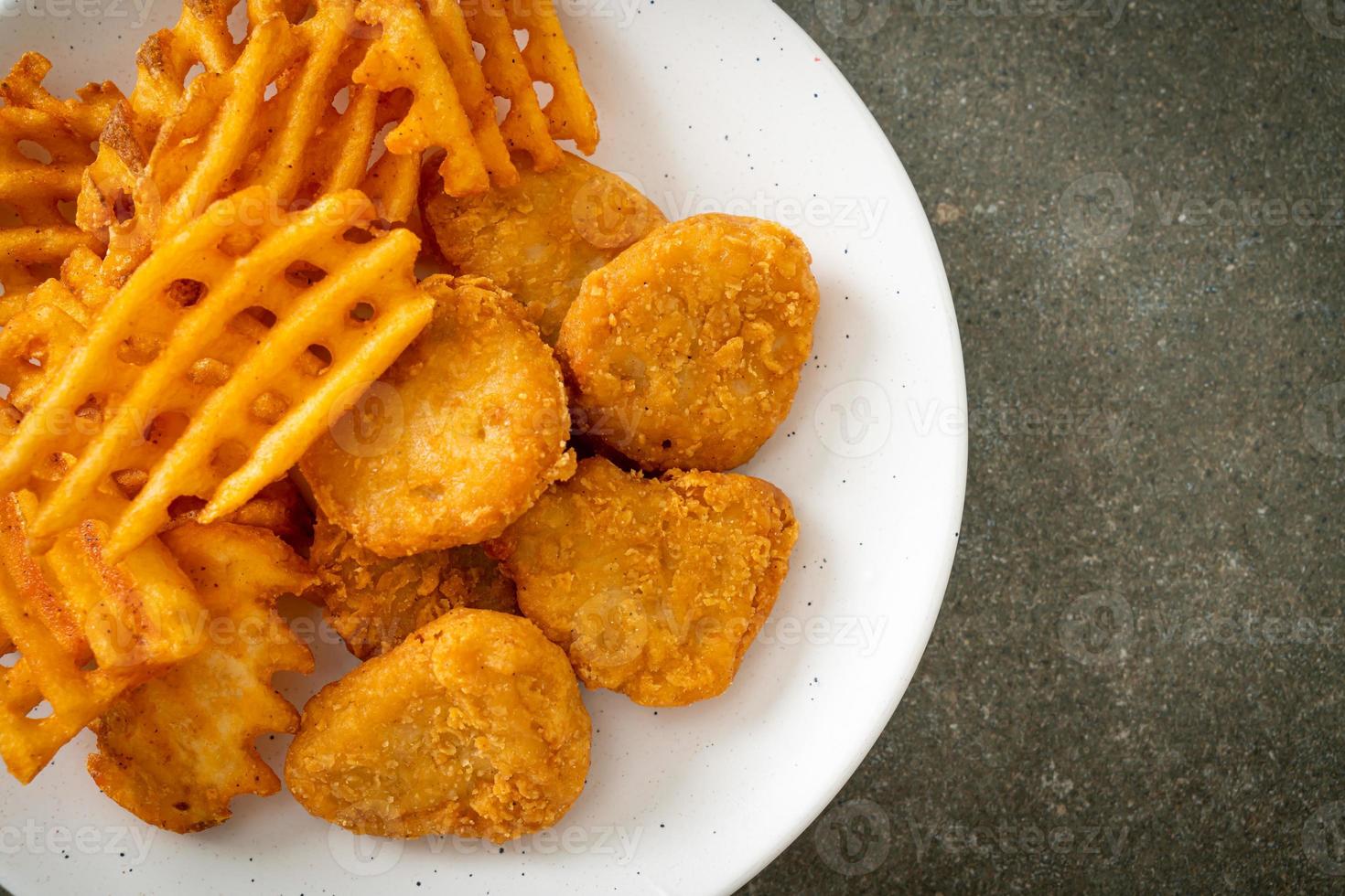 gebratene Chicken Nuggets mit Bratkartoffeln auf Teller foto