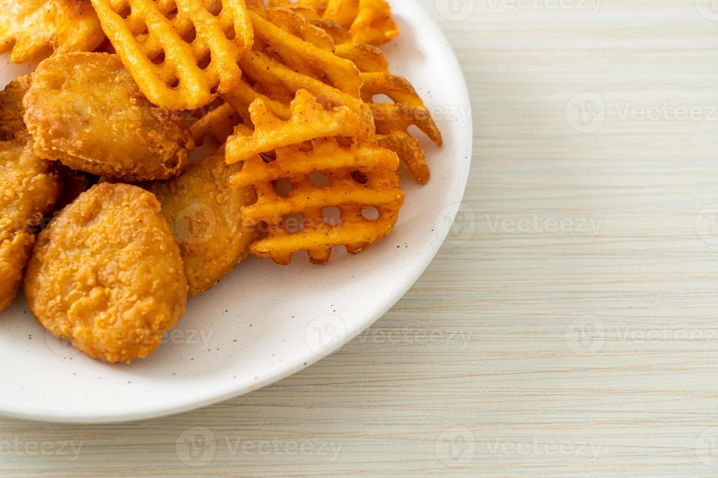 gebratene Chicken Nuggets mit Bratkartoffeln auf Teller foto