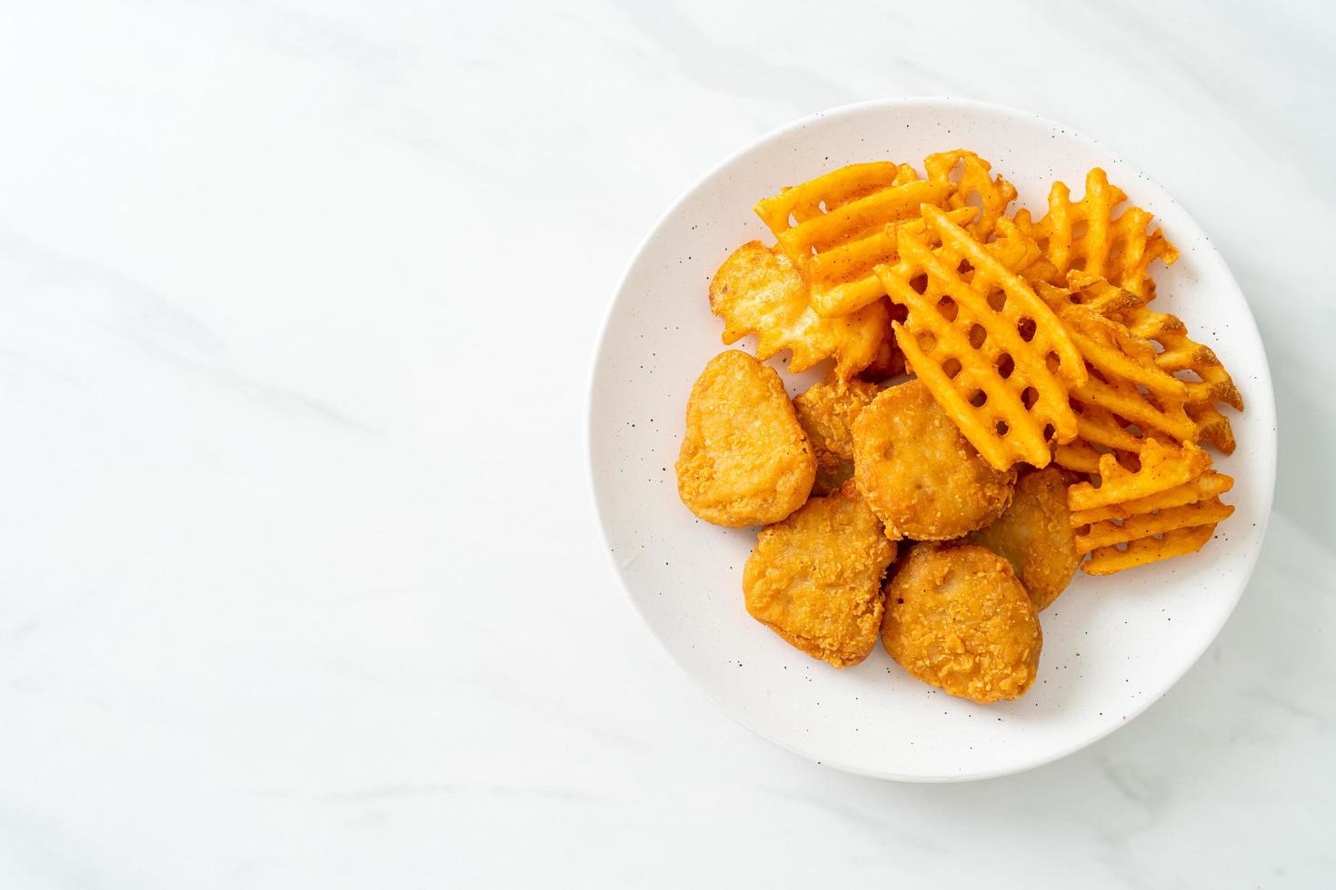 gebratene Chicken Nuggets mit Bratkartoffeln auf Teller foto