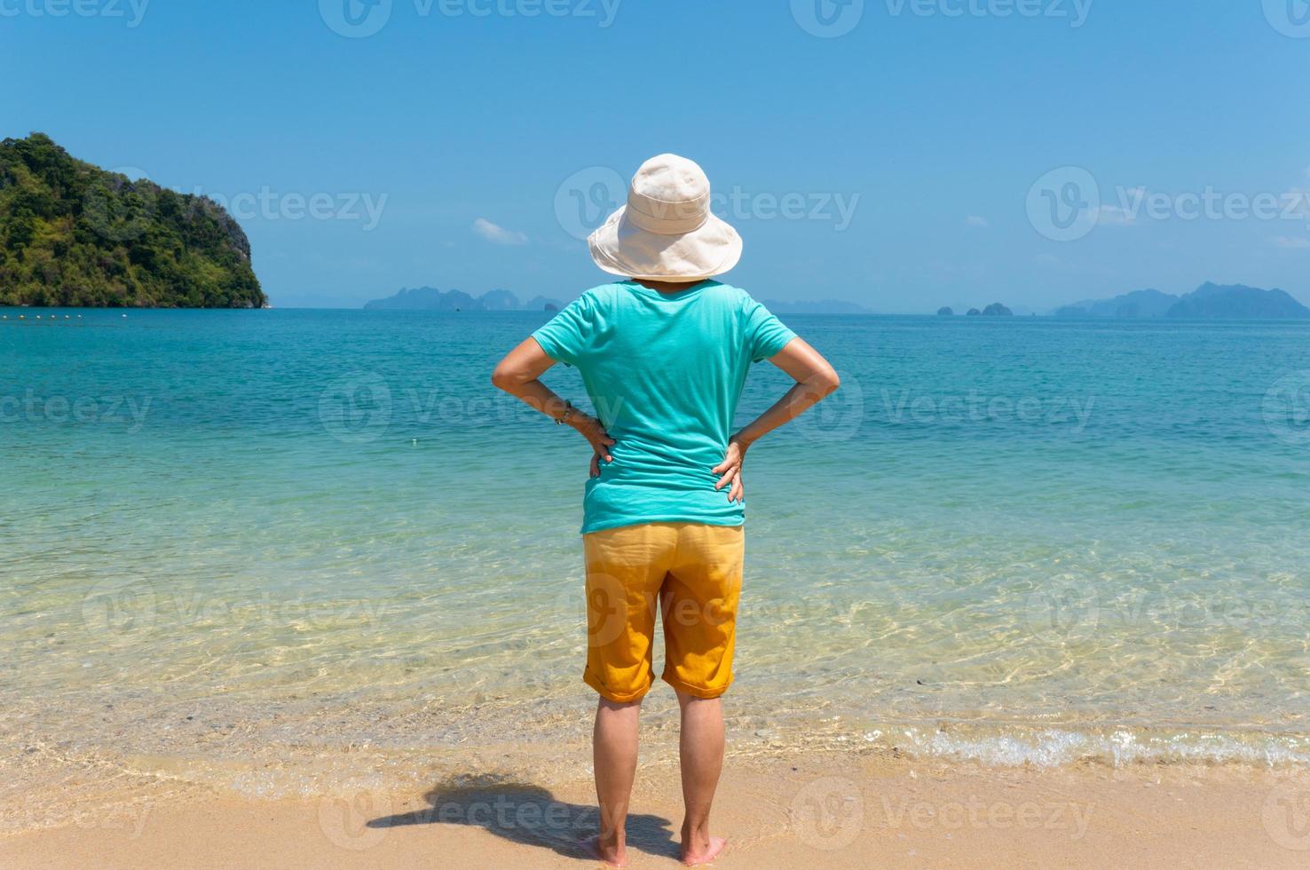 Rückansicht Porträt einer älteren Frau genießen Sie den weißen Strand und das blaue Meer der tropischen Insel während der Sommerferien foto