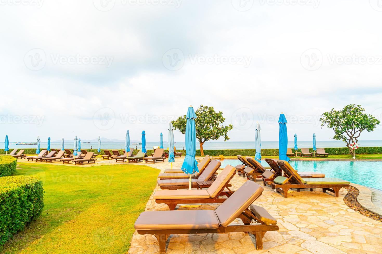 Liegepool oder Bettpool und Sonnenschirm um den Pool mit Meeresstrandhintergrund in Pattaya in Thailand foto