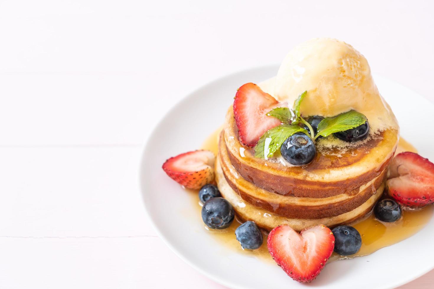 Souffle-Pfannkuchen mit Blaubeeren, Erdbeeren, Honig und Vanilleeis foto