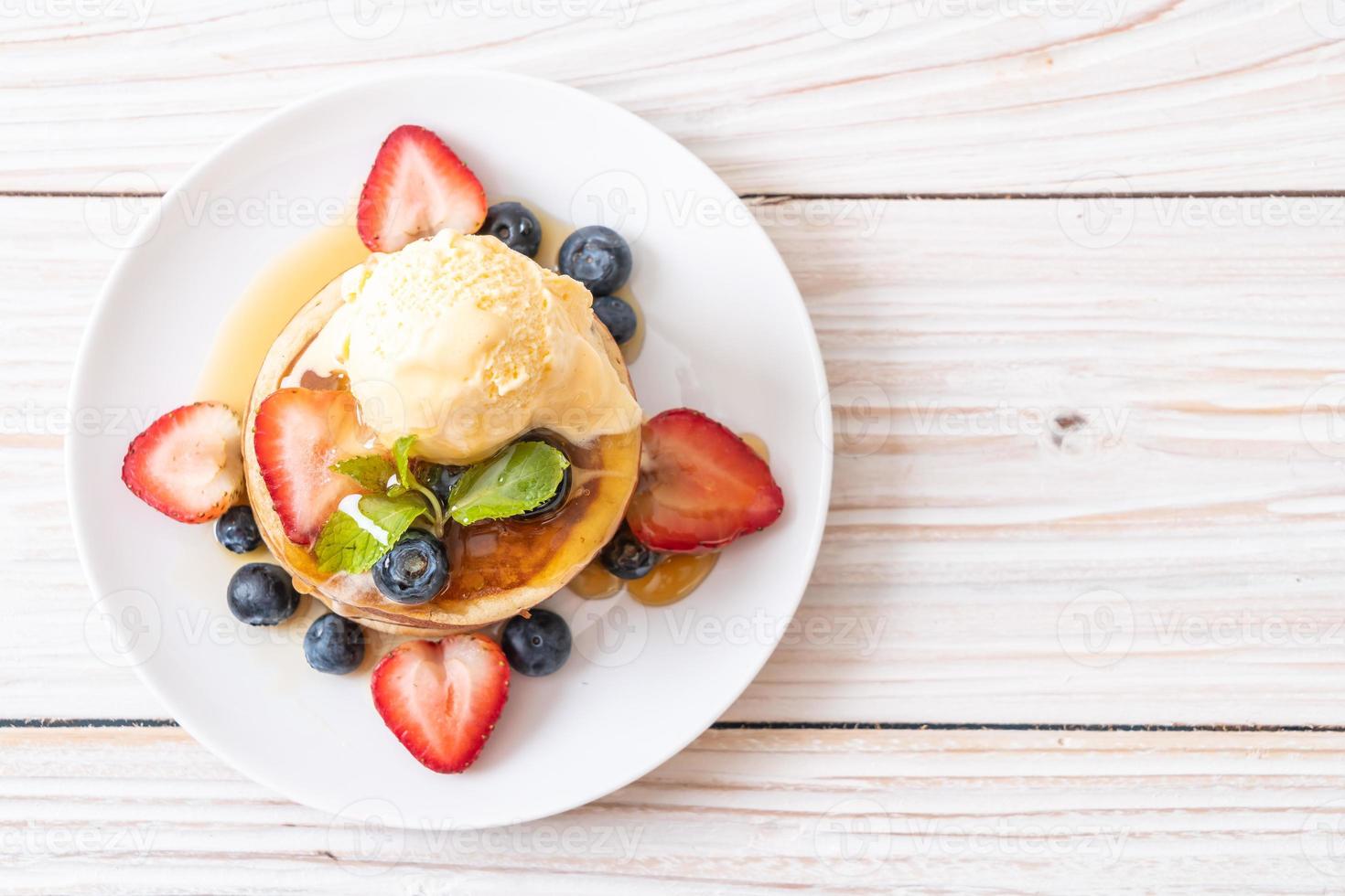 Souffle-Pfannkuchen mit Blaubeeren, Erdbeeren, Honig und Vanilleeis foto