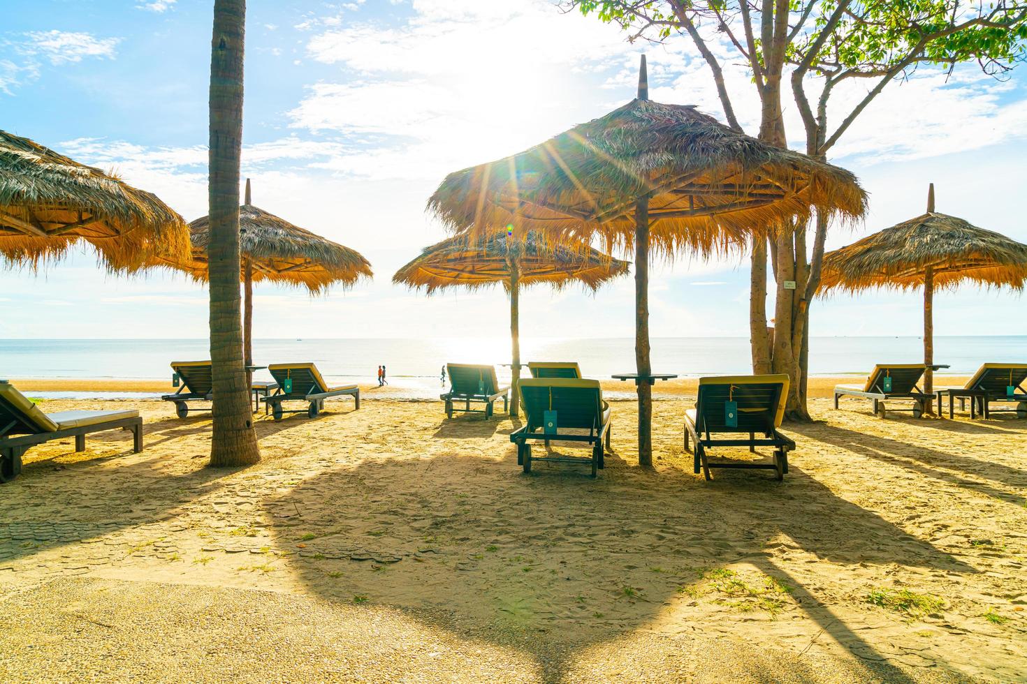 Sonnenschirme und Strandkörbe mit Kokospalmen und Meeresstrandhintergrund und blauem Himmel - Urlaubs- und Urlaubskonzept foto