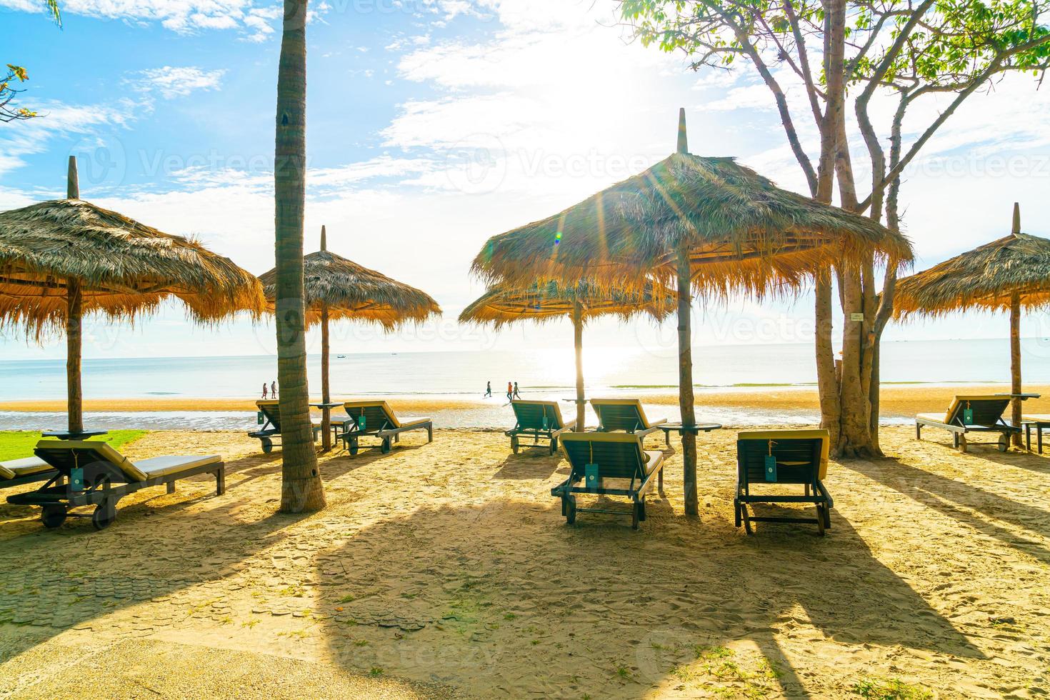 Sonnenschirme und Strandkörbe mit Kokospalmen und Meeresstrandhintergrund und blauem Himmel - Urlaubs- und Urlaubskonzept foto