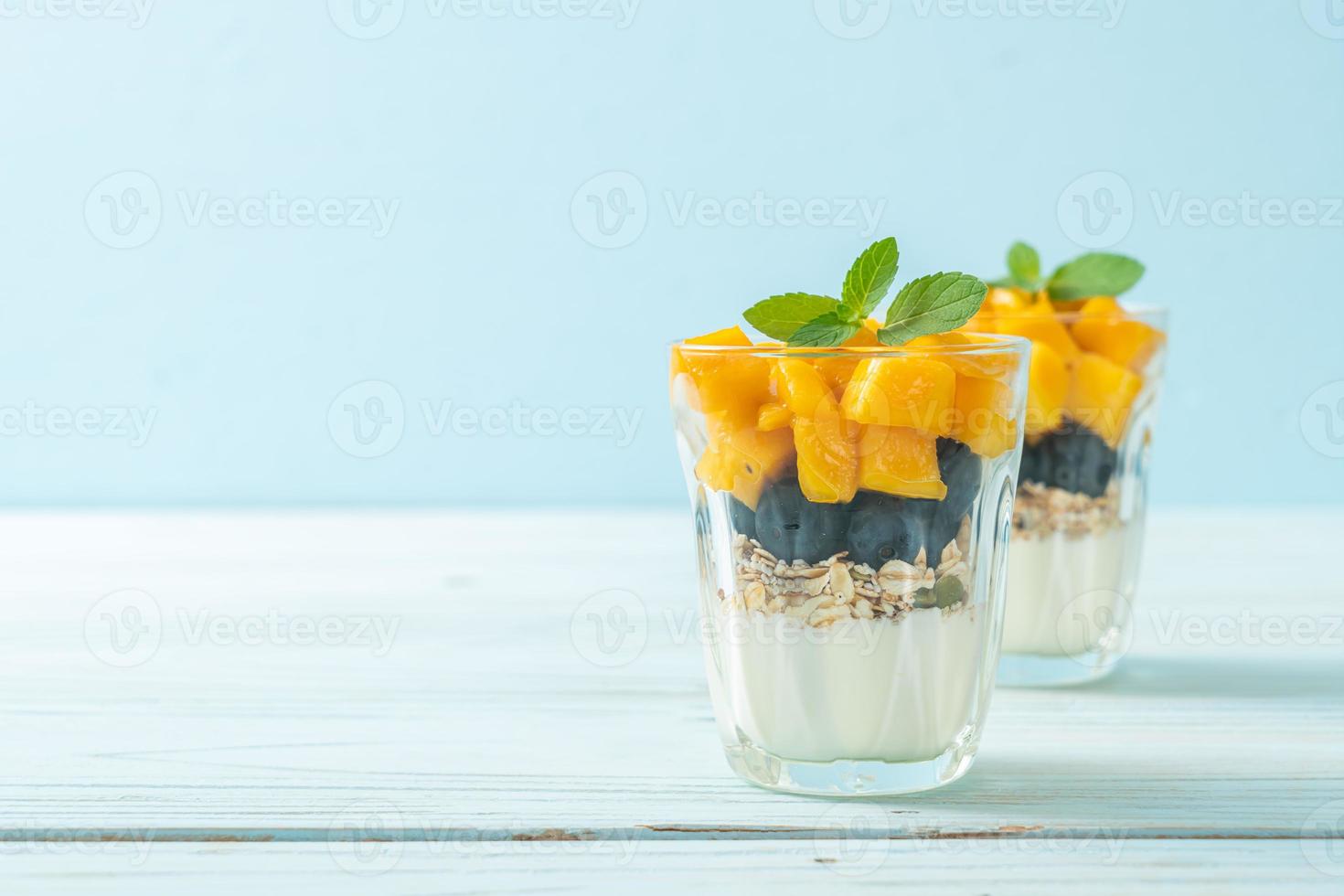 hausgemachte frische Mango und frische Heidelbeeren mit Joghurt und Müsli - gesunder Ernährungsstil foto