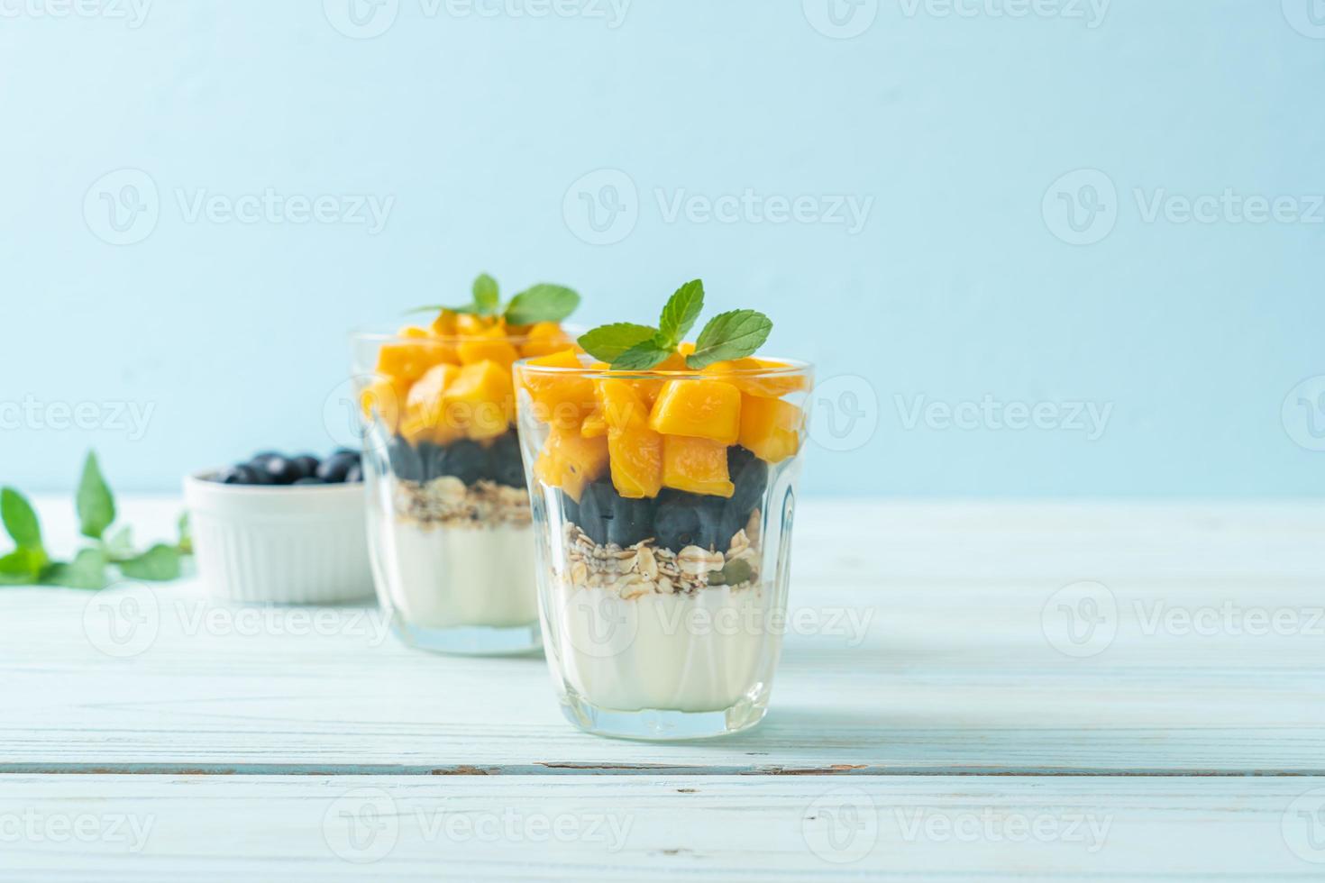 hausgemachte frische Mango und frische Heidelbeeren mit Joghurt und Müsli - gesunder Ernährungsstil foto