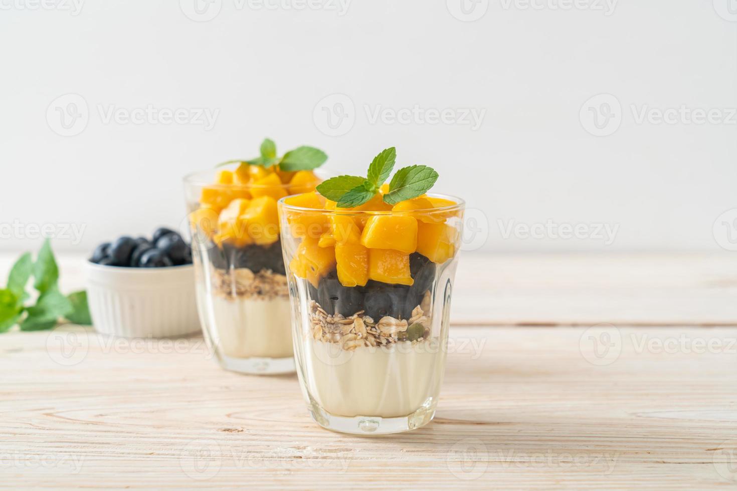 hausgemachte frische Mango und frische Heidelbeeren mit Joghurt und Müsli - gesunder Ernährungsstil foto