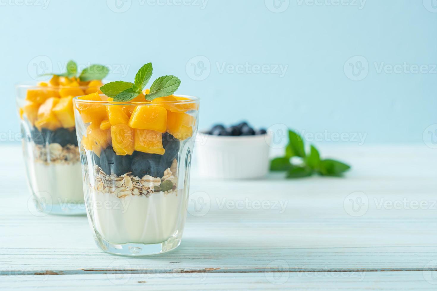 hausgemachte frische Mango und frische Heidelbeeren mit Joghurt und Müsli - gesunder Ernährungsstil foto