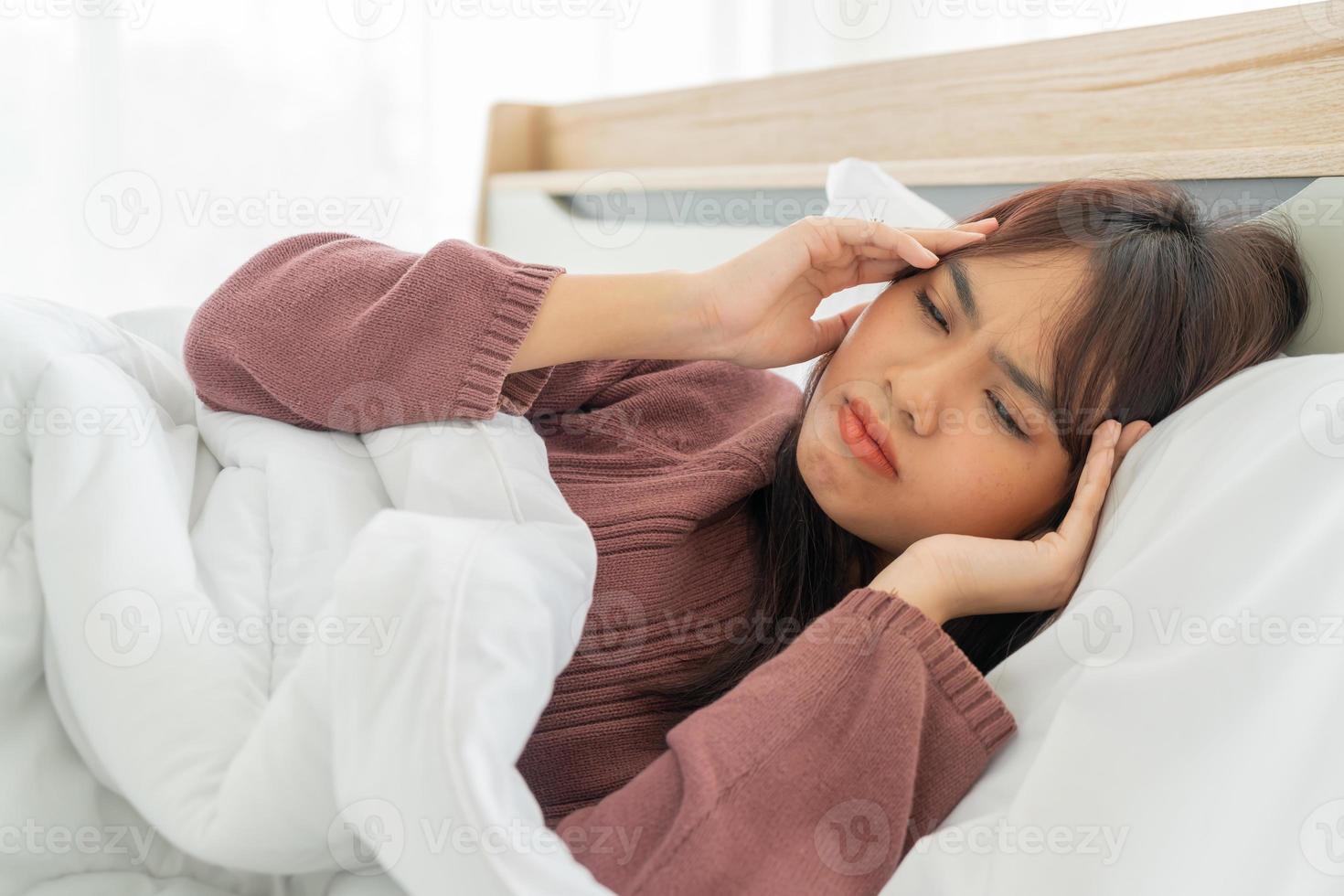 Asiatin mit Kopfschmerzen und schlafend im Bett foto