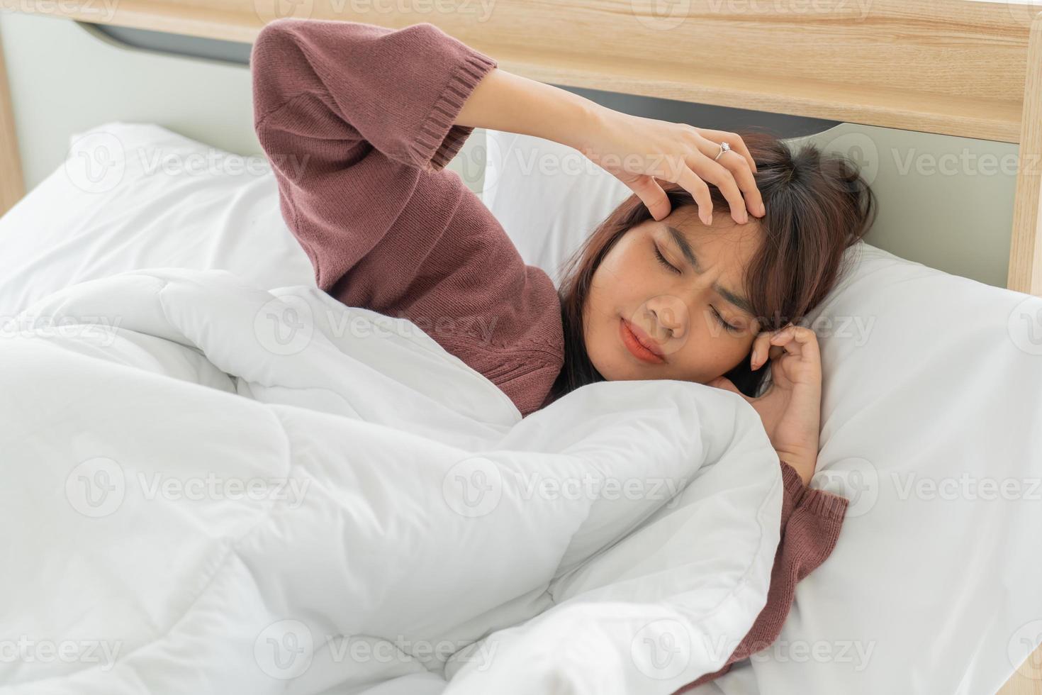 Asiatin mit Kopfschmerzen und schlafend im Bett foto