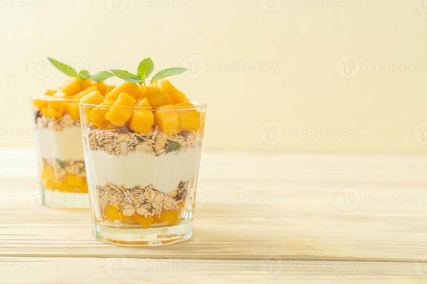 frischer Mangojoghurt mit Müsli im Glas - gesunder Food-Style foto