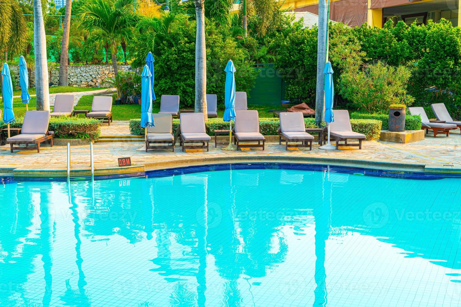 Liegepools und Sonnenschirme rund um den Swimmingpool mit Kokospalmen - Urlaubs- und Urlaubskonzept foto
