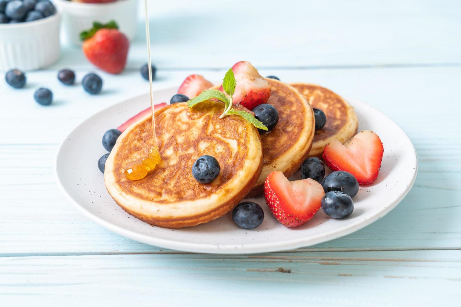 Souffle Pancake mit frischen Blaubeeren, frischen Erdbeeren und Honig foto