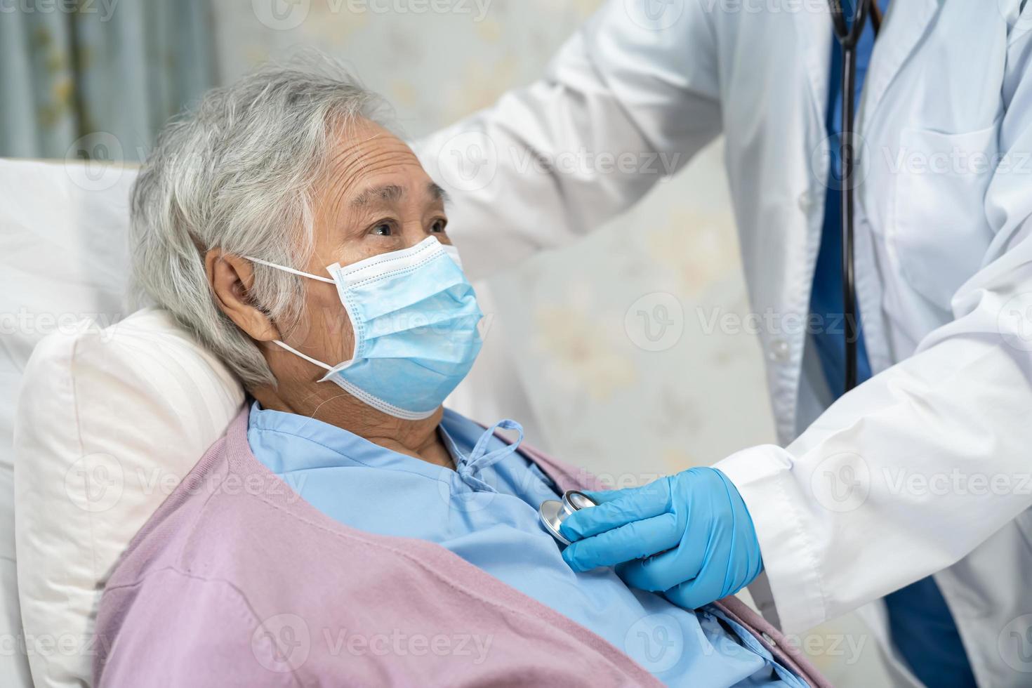 Arzt, der ein Stethoskop verwendet, um asiatische Senioren oder ältere Frauen mit einer Gesichtsmaske im Krankenhaus zu überprüfen, um die Infektion mit dem Covid-19-Coronavirus zu schützen. foto