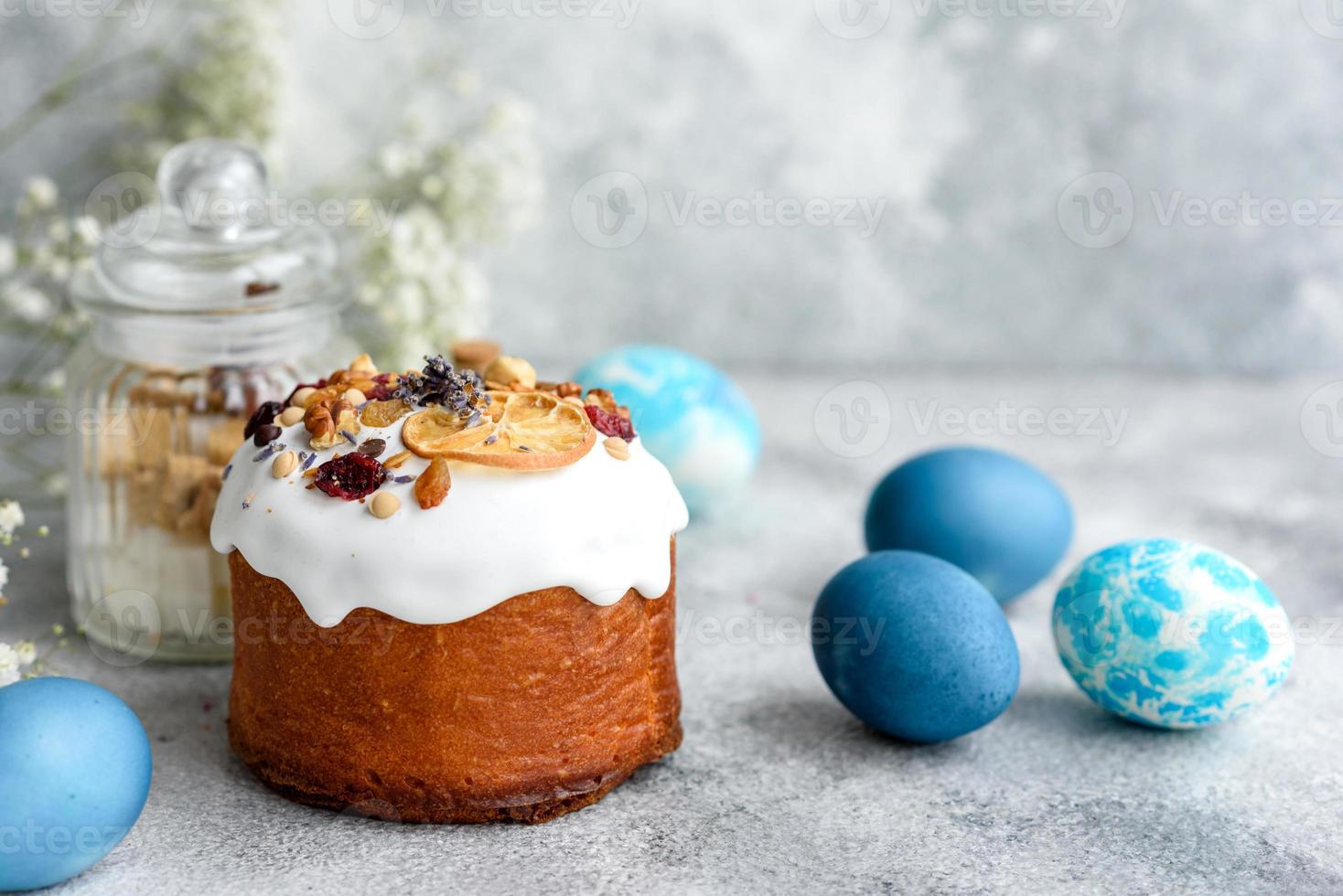 festliche Kuchen mit weißer Glasur, Nüssen und Rosinen mit Ostereiern auf dem festlichen Tisch foto