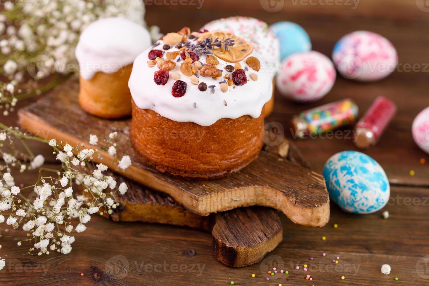 festliche Kuchen mit weißer Glasur, Nüssen und Rosinen mit Ostereiern auf dem festlichen Tisch foto