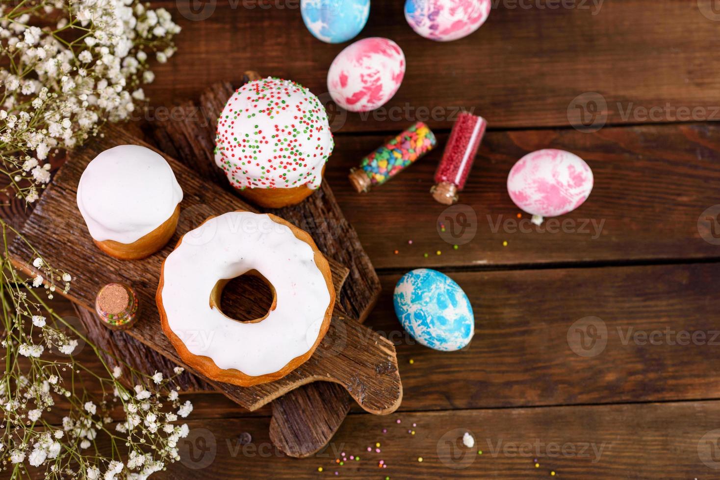 festliche Kuchen mit weißer Glasur, Nüssen und Rosinen mit Ostereiern auf dem festlichen Tisch foto