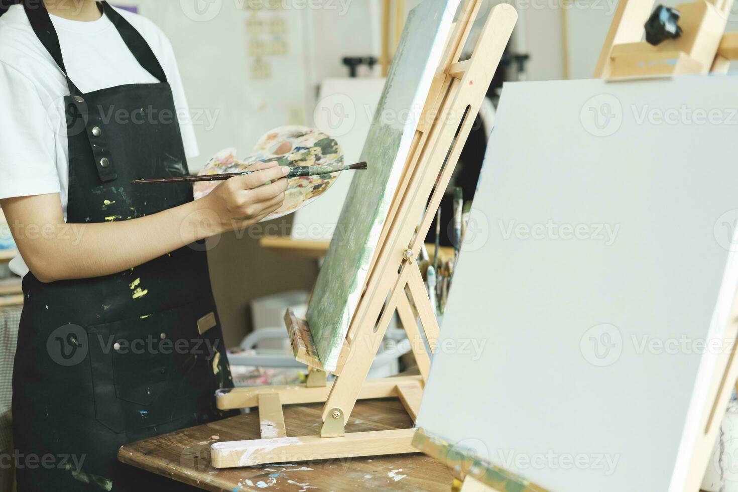 jung asiatisch weiblich Künstler Gemälde auf Segeltuch tun Kunst Projekte auf ihr Studio. foto