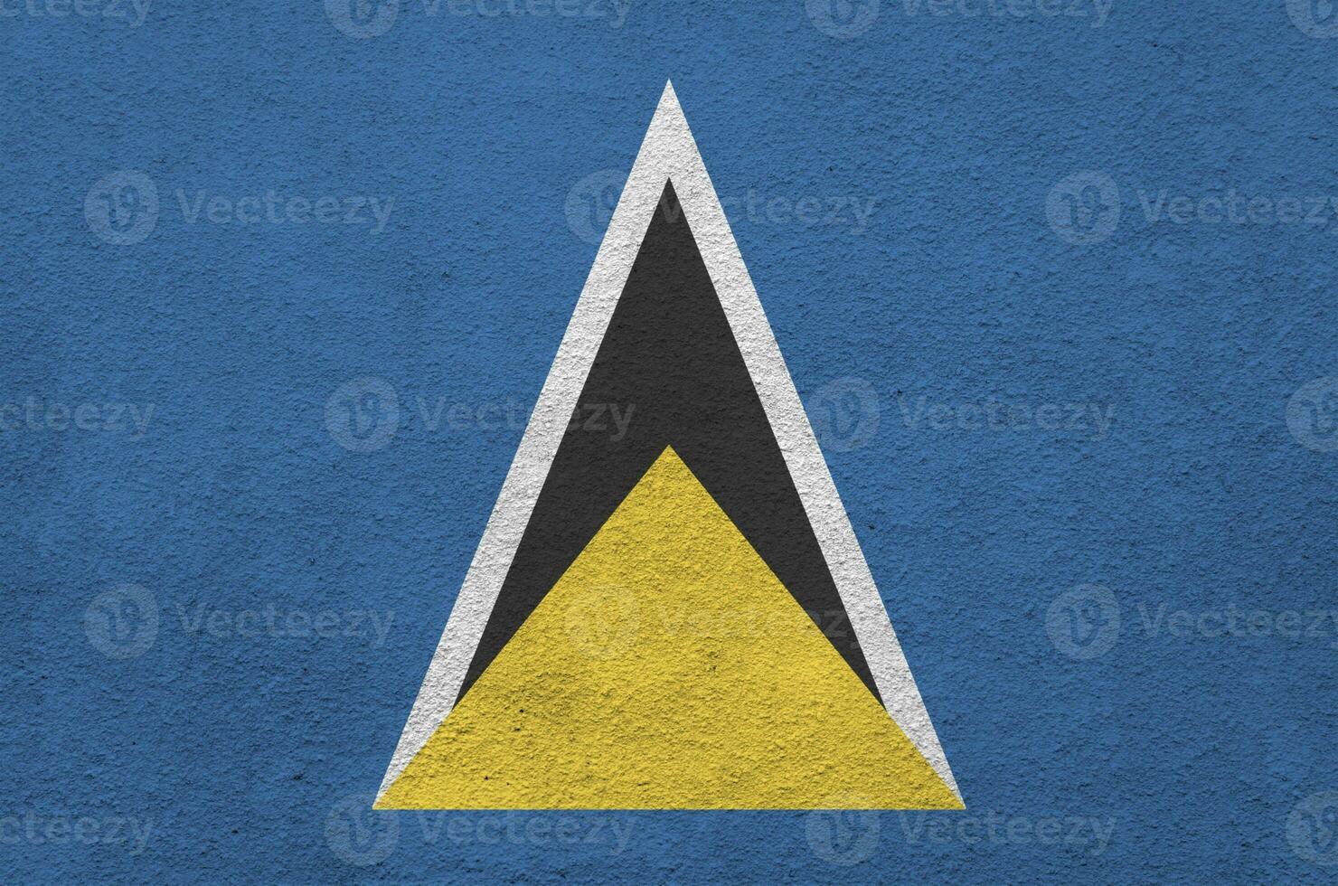 st. lucia-flagge in hellen farben auf alter reliefputzwand dargestellt. strukturierte Fahne auf rauem Hintergrund foto