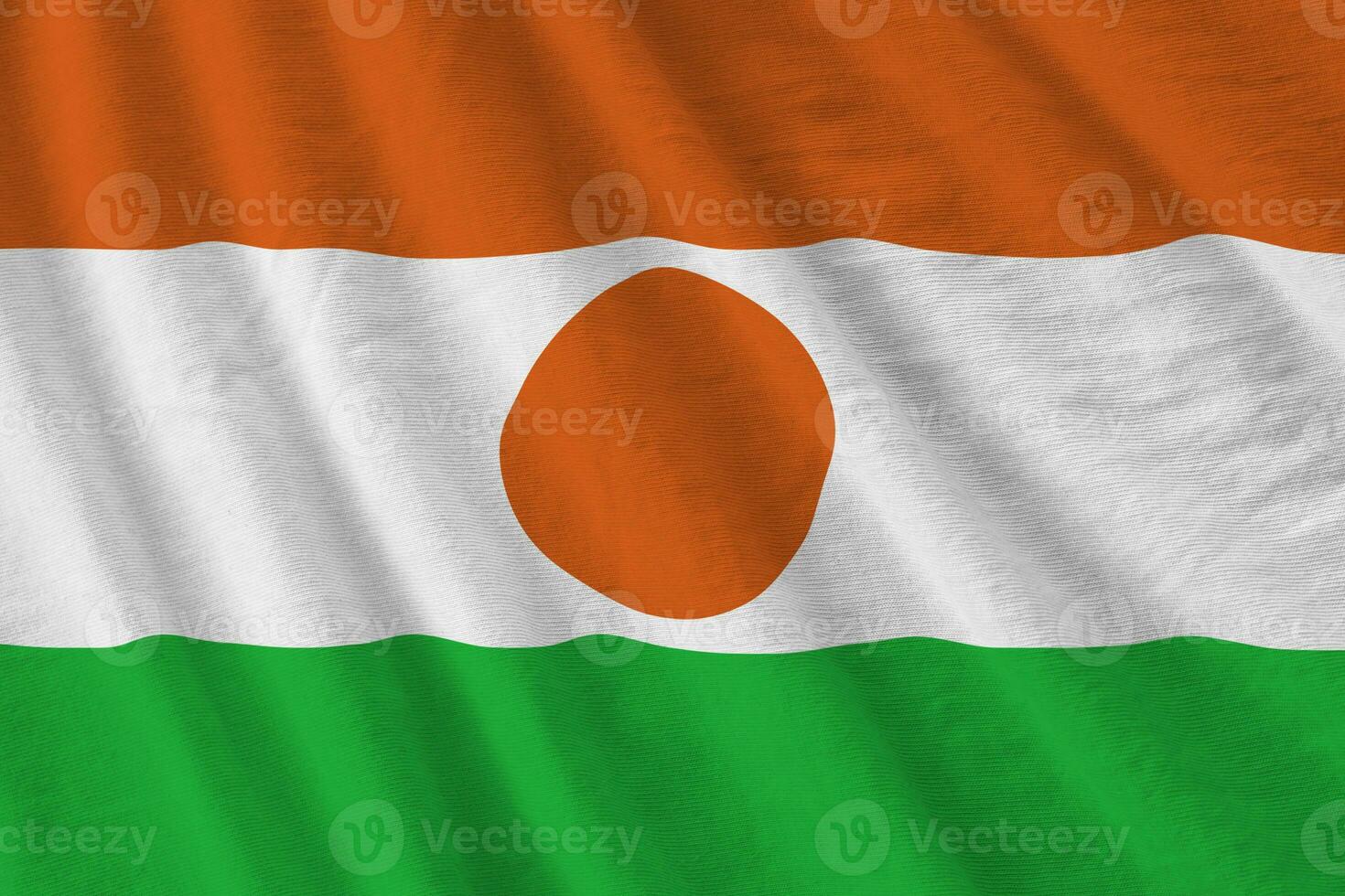 niger-flagge mit großen falten, die im innenbereich unter dem studiolicht wehen. die offiziellen symbole und farben im banner foto