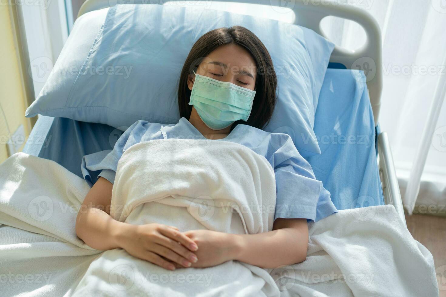 traurig asiatisch geduldig Frau Lügen auf das Krankenhaus Bett und tragen ein Gesicht Maske zu schützen Coronavirus. Konzept von Gesundheit Pflege, Quarantäne Coronavirus COVID-19, und Gesundheit Versicherung. foto