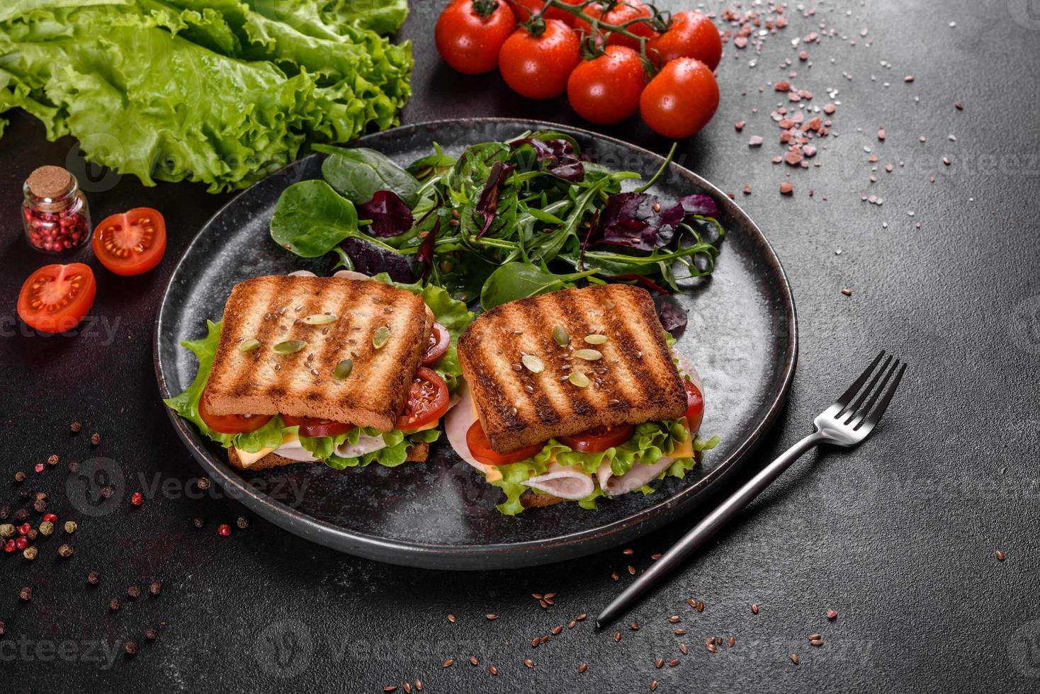 leckeres Sandwich mit knusprigem Toast, Schinken, Salat und Tomaten foto