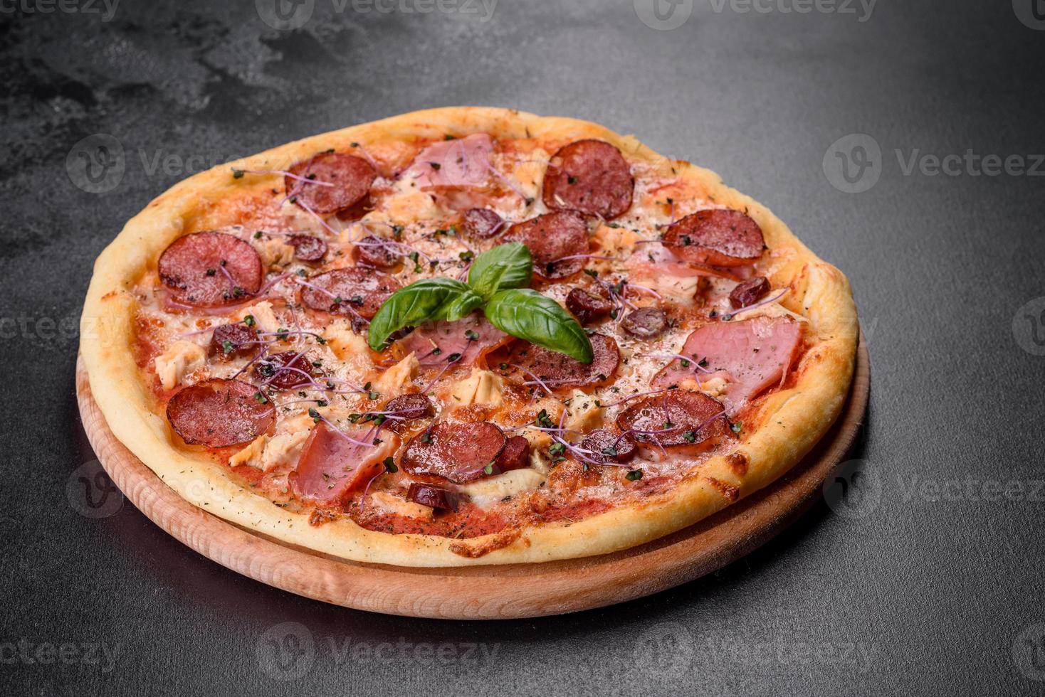 leckere frische Ofenpizza mit Tomaten, Salami und Speck auf dunklem Betongrund foto