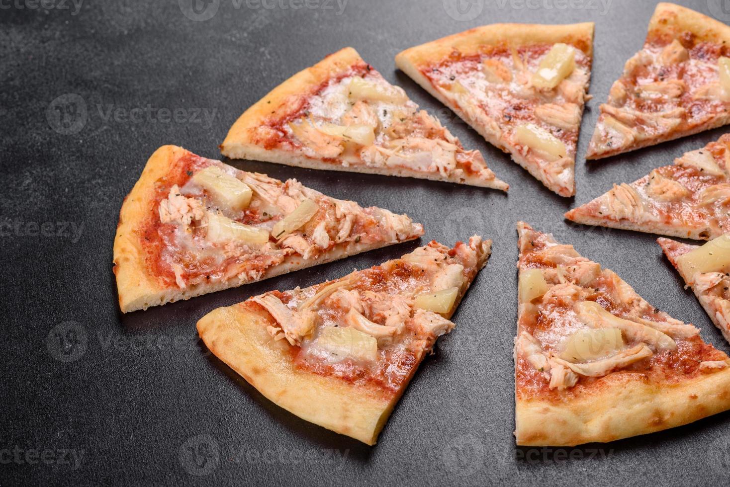leckere frische Ofenpizza mit Tomaten, Käse und Ananas auf dunklem Betongrund foto