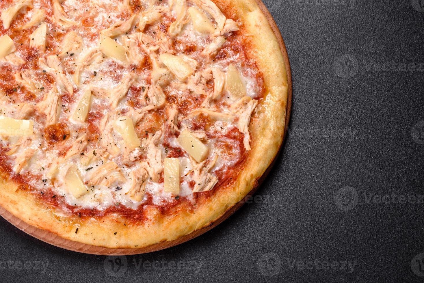 leckere frische Ofenpizza mit Tomaten, Käse und Ananas auf dunklem Betongrund foto