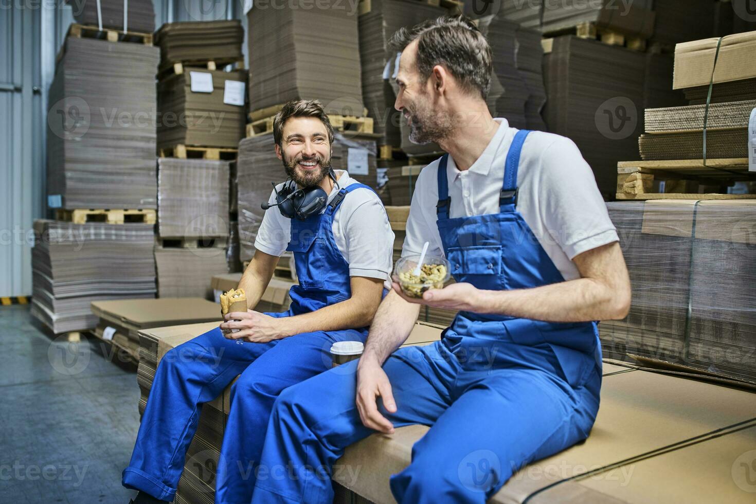 zwei glücklich Arbeitskräfte haben Mittagessen brechen im Fabrik foto