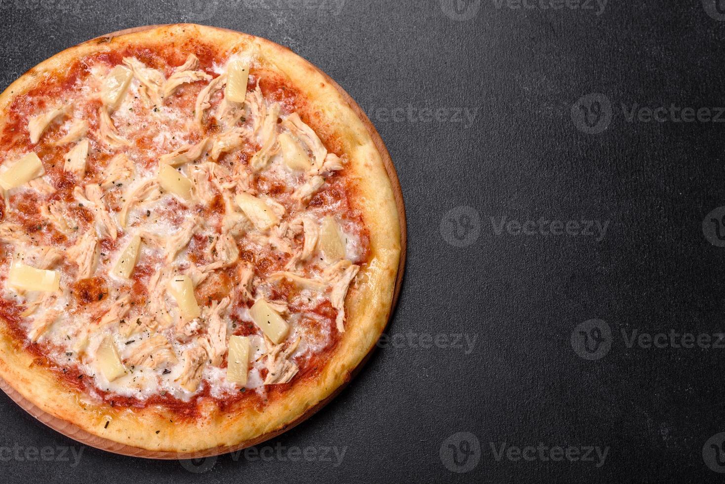 leckere frische Ofenpizza mit Tomaten, Käse und Ananas auf dunklem Betongrund foto