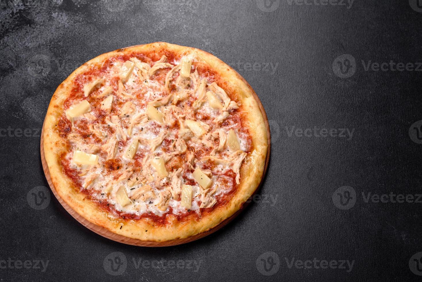 leckere frische Ofenpizza mit Tomaten, Käse und Ananas auf dunklem Betongrund foto