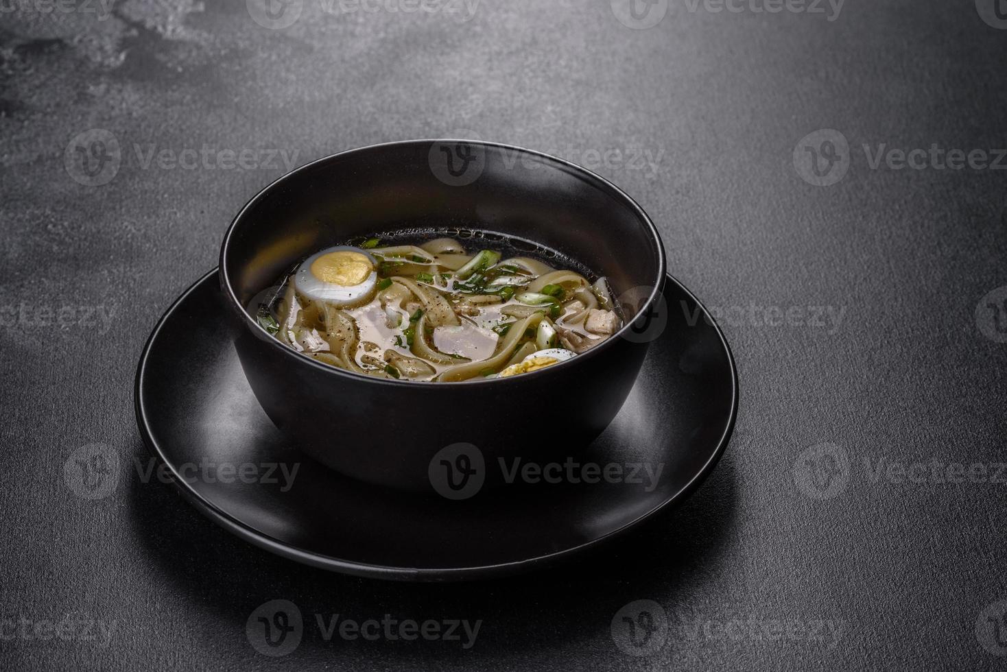 frische leckere heiße Suppe mit Nudeln und Wachtelei in einem schwarzen Teller foto