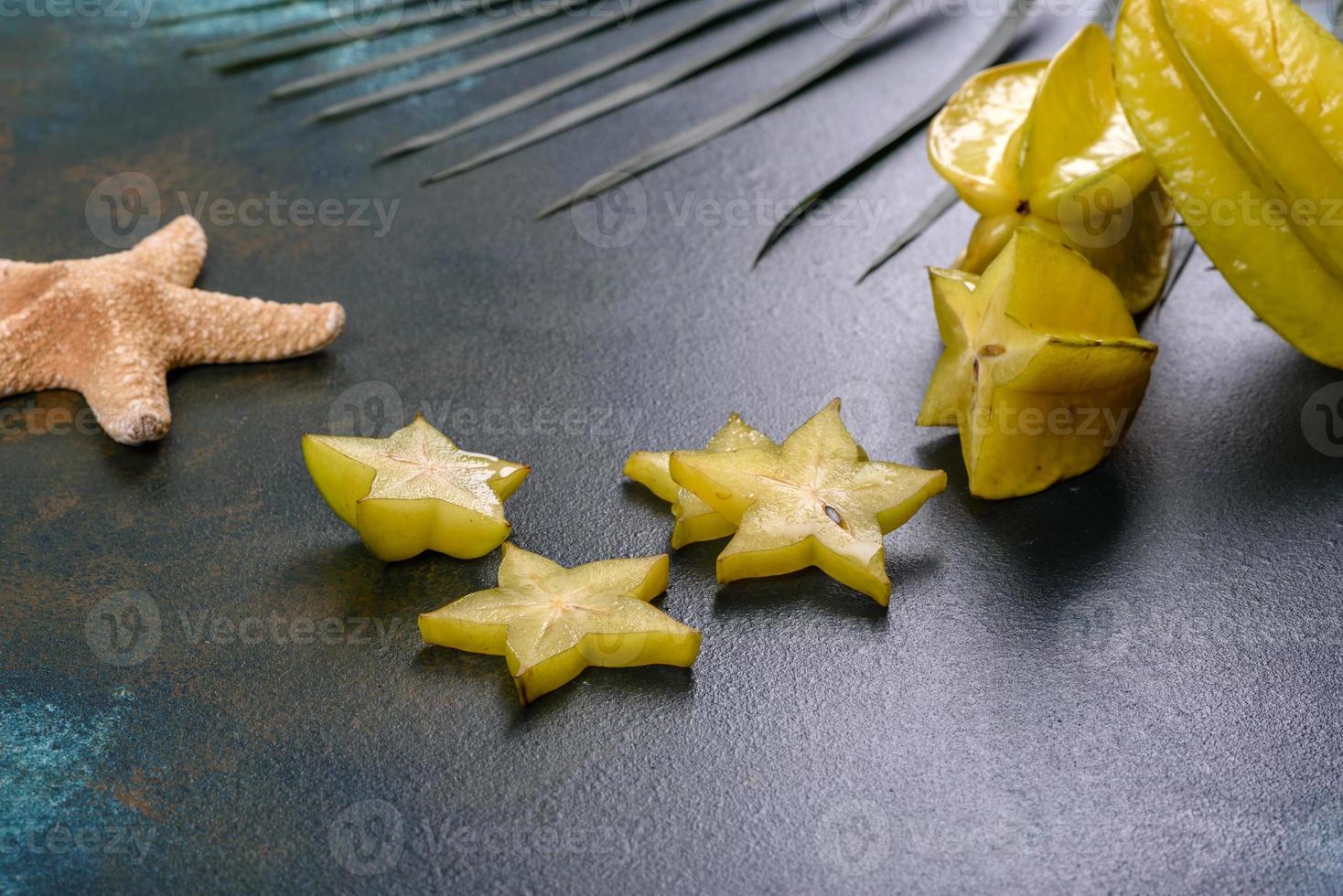 Fruchtkarambolen, Strandzubehör und Blätter einer tropischen Pflanze auf farbigem Papier foto