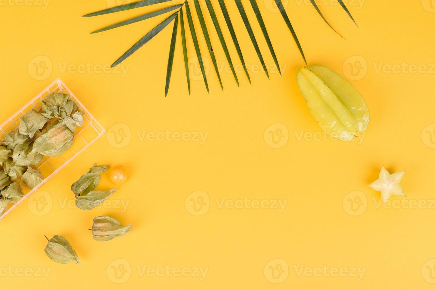 Fruchtkarambolen, Strandzubehör und Blätter einer tropischen Pflanze auf farbigem Papier foto